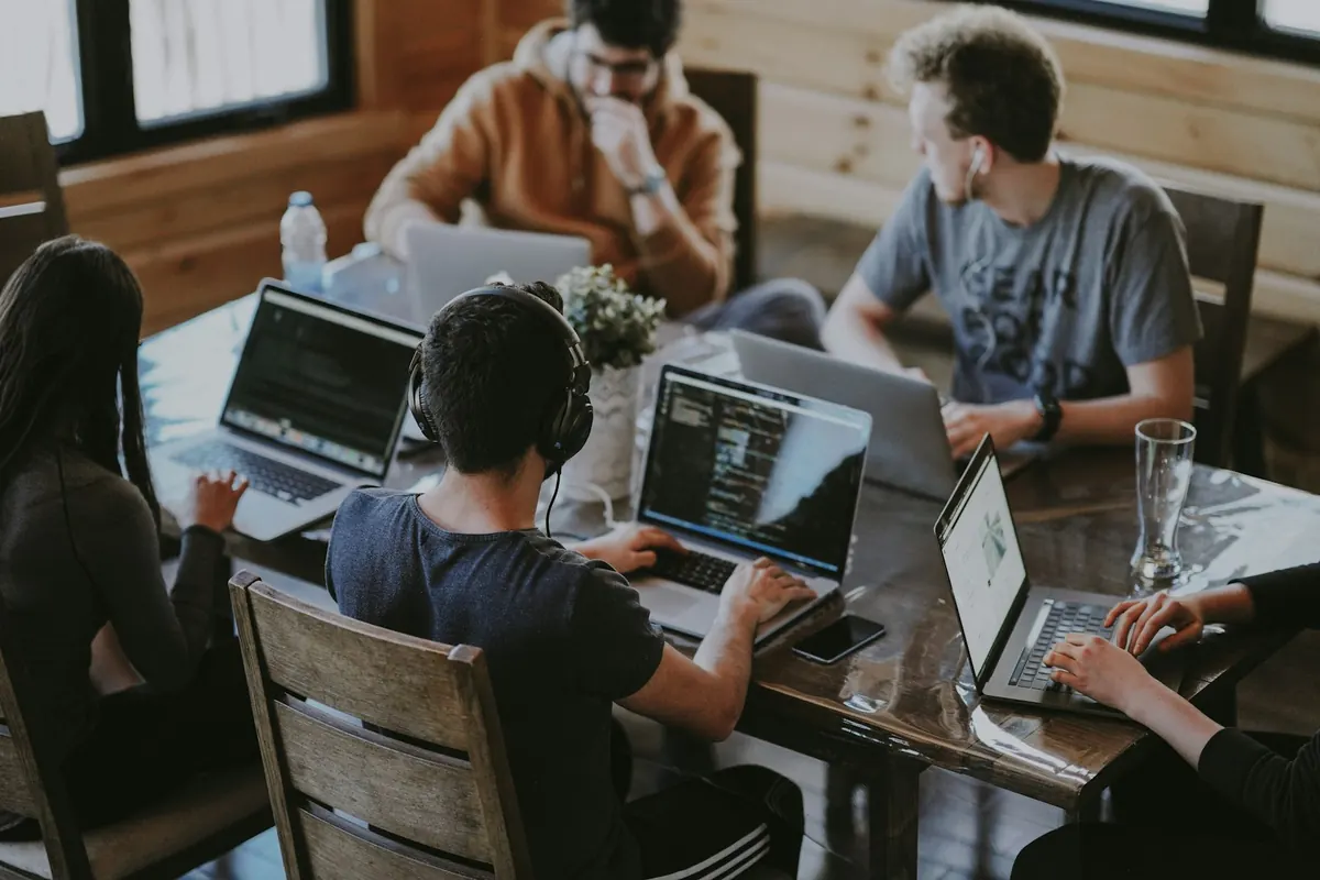 Agency team working together on laptops around a wooden table